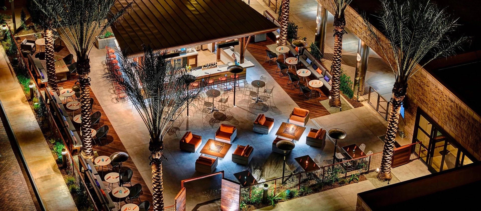 Fire pits and lounge seating at E.D.B. glowing at night among the palms